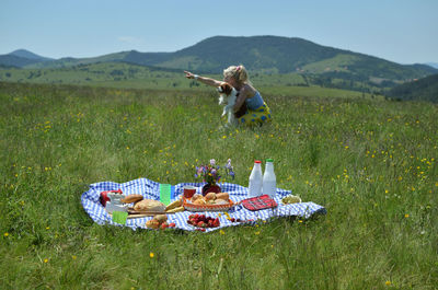 Lush picnic with lady showing something in distance to her dog and with hills in background