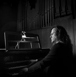 Side view of mature man playing piano