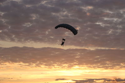 Low angle view of silhouette person paragliding against sky