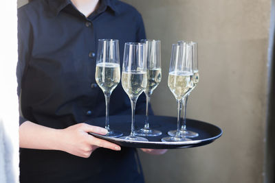 Midsection of waitress holding champagne flutes