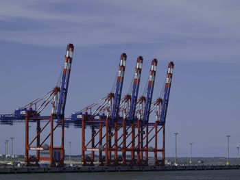 Cranes at commercial dock against sky