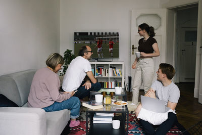 Family talking to daughter while watching football on tv in living room at home