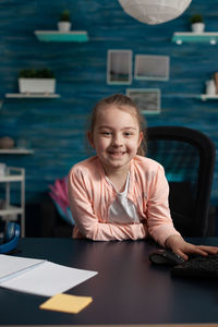 Portrait of girl sitting by table at home