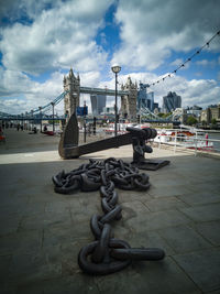 Chain on bridge over river against sky in city