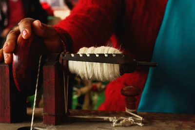 Midsection of woman weaving loom in workshop