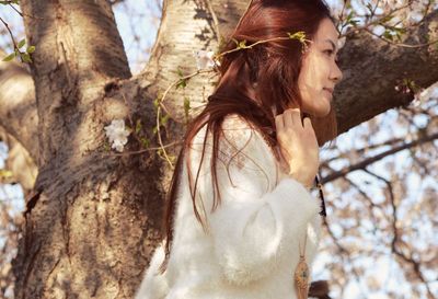 Young woman looking at tree trunk