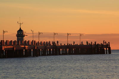 Silhouette pier over sea against sky during sunset