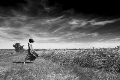 Side view of woman on field against sky