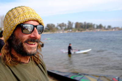 Close-up of smiling man wearing sunglasses against lake