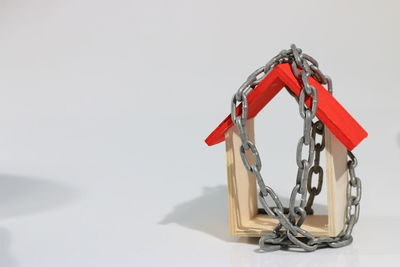 Close-up of red chain hanging on table against white background