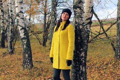 Portrait of young woman standing in forest during autumn