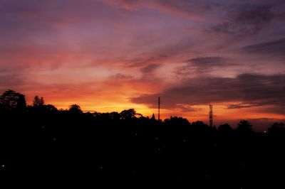 Silhouette trees against dramatic sky during sunset