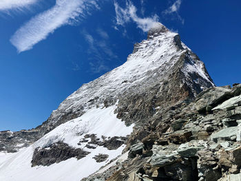 Low angle view of snowcapped mountain against blue sky