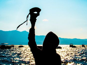 Rear view of silhouette woman standing by sea against sky