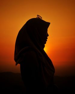 Side view of silhouette woman against orange sky