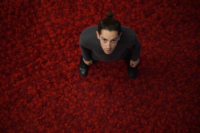 Portrait of a young man sitting on red floor