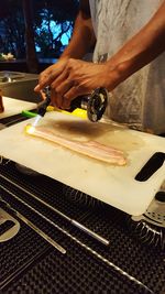 Midsection of man burning cutting board with butane torch in kitchen