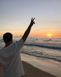 Rear view of person at beach during sunset