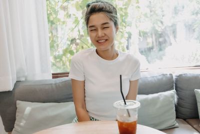 Young woman using mobile phone while sitting on sofa at home