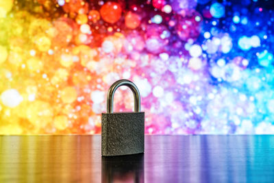 Close-up of padlock on table against colorful illuminated lights