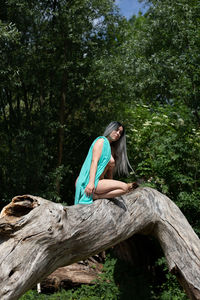 Woman sitting on wood in forest