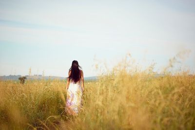 Rear view of woman standing on field against sky