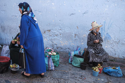 Women sitting on cobblestone street