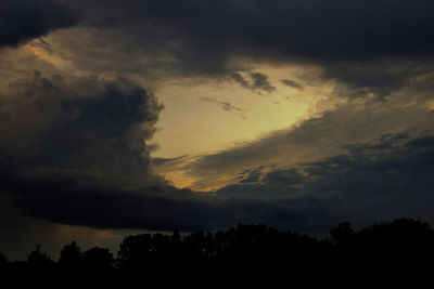 Low angle view of silhouette trees against dramatic sky