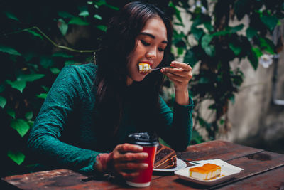 Young woman using mobile phone while sitting on table