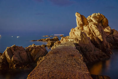 Rock formation on beach against sky