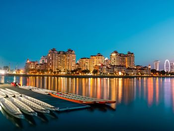 River by illuminated buildings against clear blue sky at night