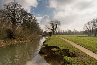 High angle view of river by grassy field against cloudy sky