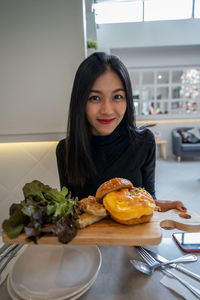 Portrait of young woman with vegetables in plate on table