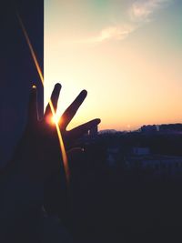 Silhouette hand holding sun during sunset