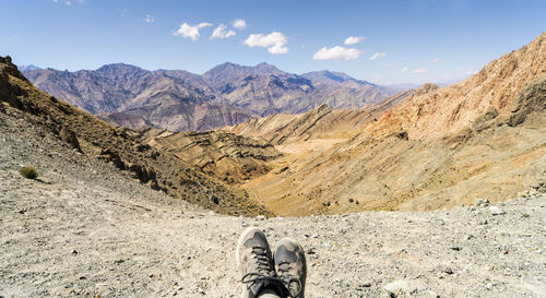 Low section of person on mountain against sky