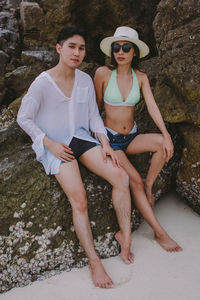 Portrait of couple sitting on rock at beach