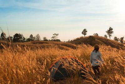 Rear view of woman standing on field against sky