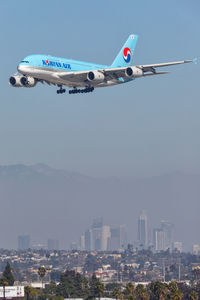 Airplane flying over city against sky