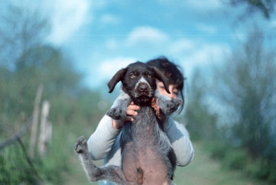 Girl holding dog on field