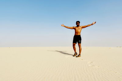 Full length of man standing on beach against clear sky