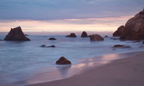 Rocks on sea against sky during sunset