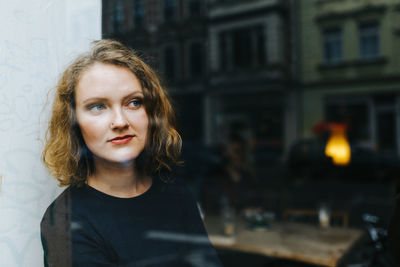 Thoughtful woman looking through window at cafe