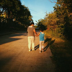 Rear view of mother and daughter walking on street