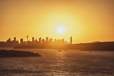 Scenic view of sea and buildings against sky during sunset