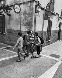 Rear view of people walking on street against buildings