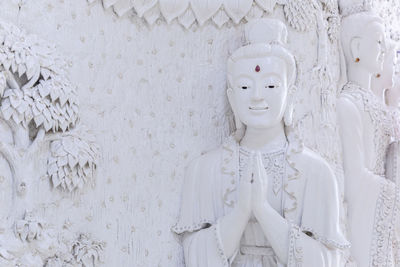 Close-up of buddha statue against white wall