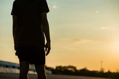 Rear view of silhouette woman standing against sky during sunset