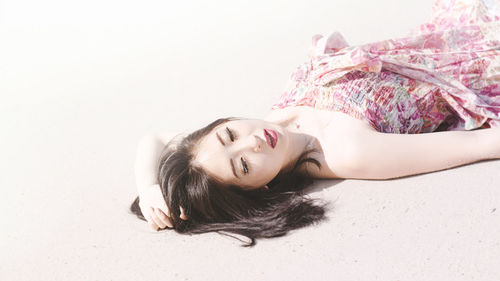 Portrait of woman lying on white background