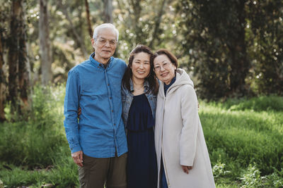 Portrait of senior active couple hugging adult daughter outside