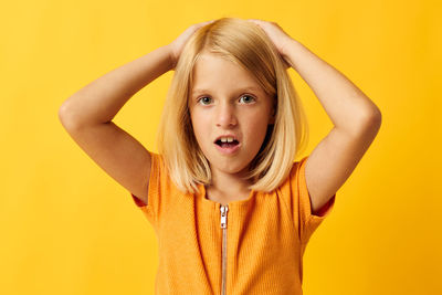 Portrait of young woman against yellow background